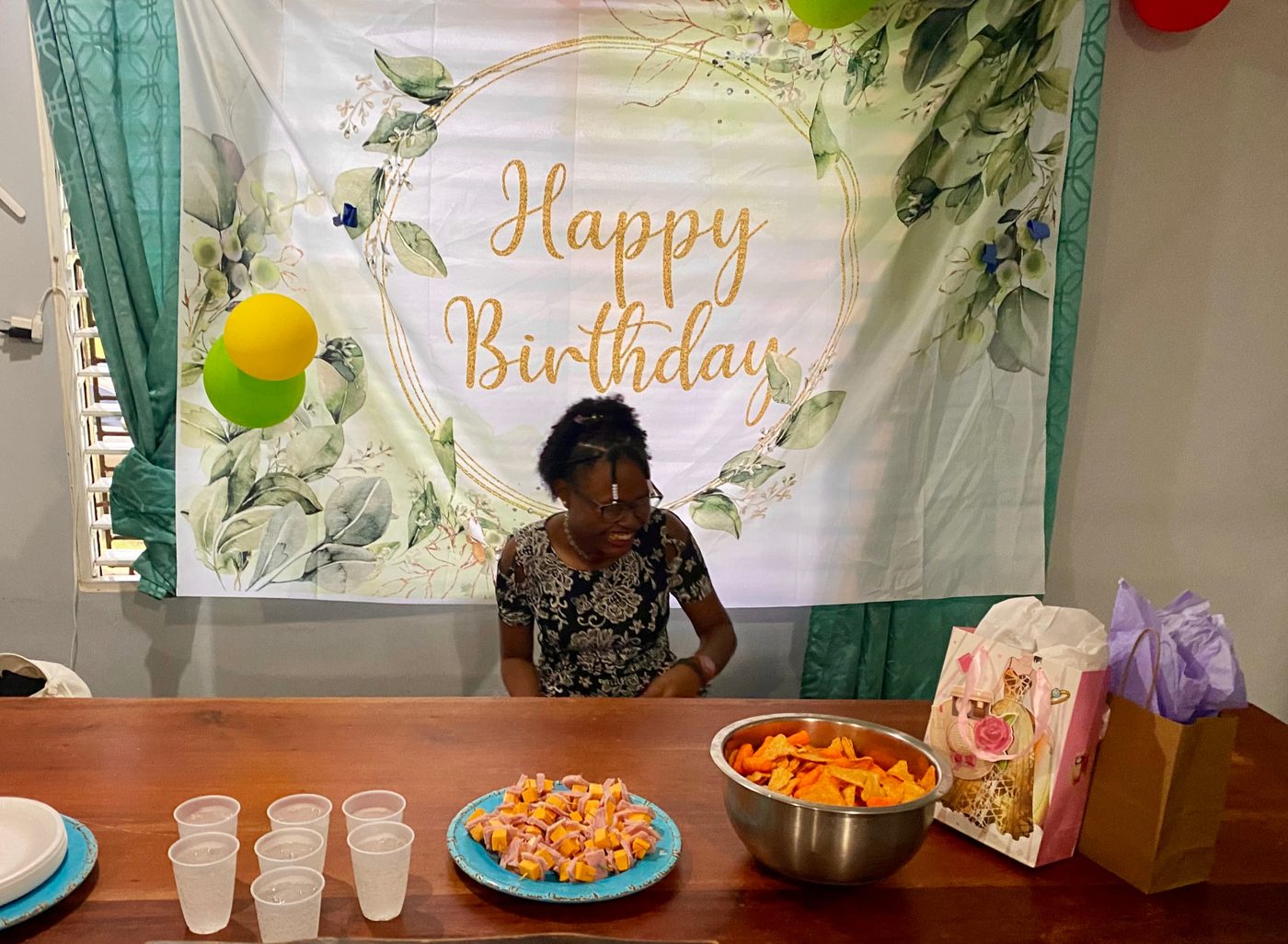 A birthday banner, balloons, and a table set with food and gifts inside the home