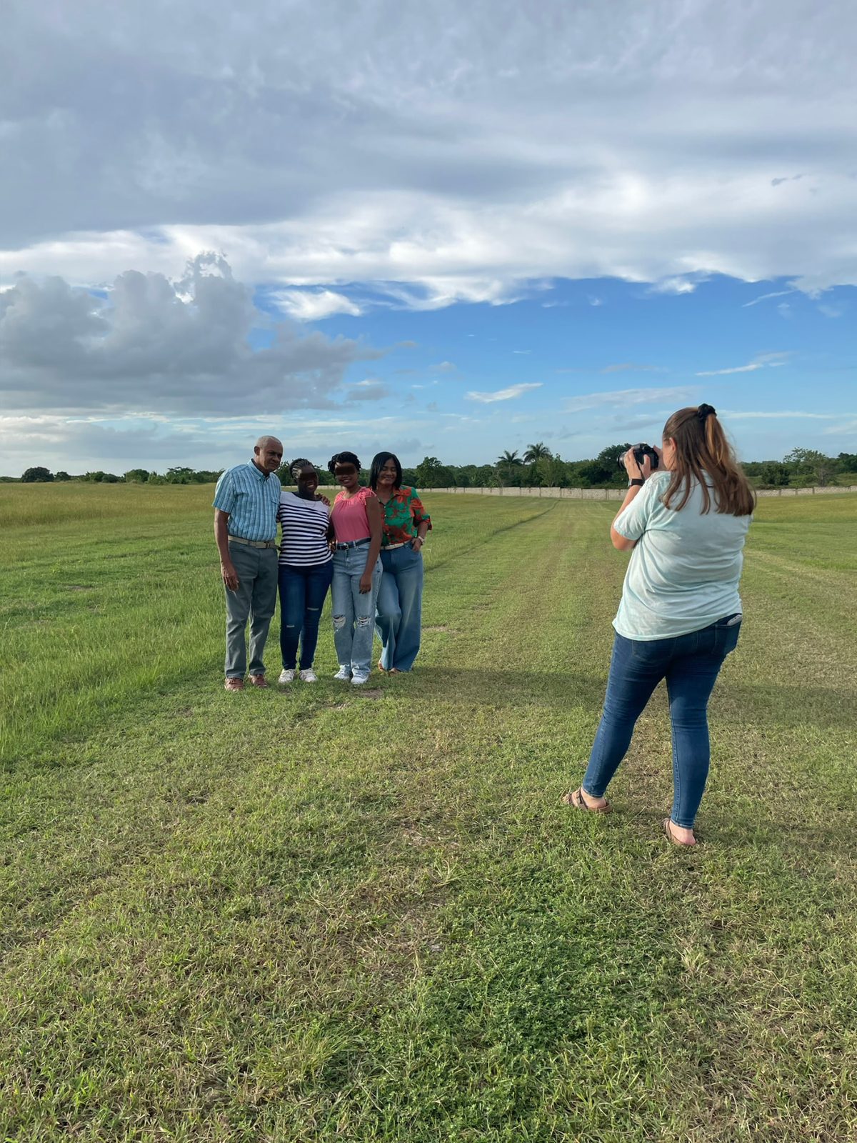 A family gathered in the open field behind the home, being photographed under a wide sky